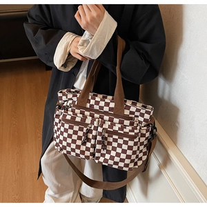 Detail showing checkered tote bag with functional zipper pockets and brown textile strap