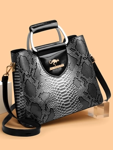 Detail of snake skin texture handbag with golden kangaroo logo and silver metal handle