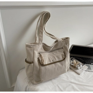 Detail of off-white corduroy tote bag with dark green trim and multiple functional pockets