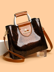 Detailed close-up of dark brown snake texture handbag with silver handle and gold logo