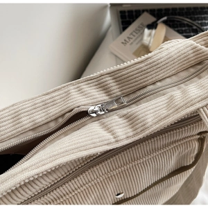 Detailed close-up of corduroy tote bag with silver zipper and magnetic snap closure