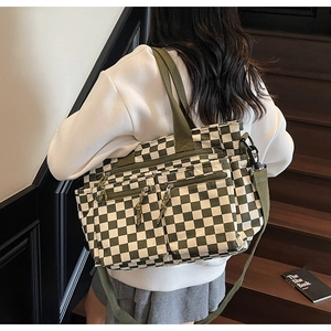 Model wearing a green checkerboard canvas tote bag with adjustable shoulder strap