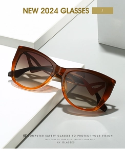 Detail of tortoise shell cat eye sunglasses with gradient brown lenses on white props