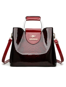 Detail of burgundy snakeskin embossed tote bag with gold kangaroo logo and round metal handle