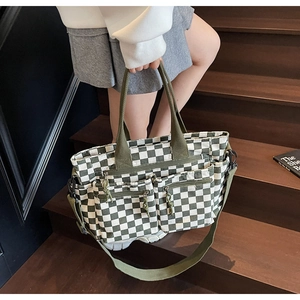 Detail of checkered tote bag showing multi-pocket structure and green shoulder strap