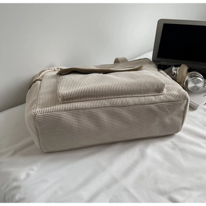 Detail of off-white corduroy tote bag showing thick ribbed fabric and front pocket