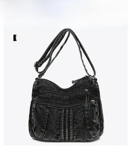 Détail de face du sac bandoulière en denim noir délavé avec trois poches zippées devant