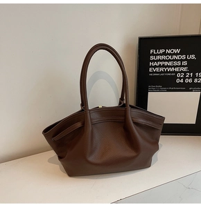 Détail du sac fourre-tout en cuir marron foncé avec grain de litchi et plis élégants