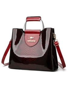 Macro detail of wine red faux snakeskin texture on leather handbag with metal logo