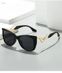 Close-up of stylish cat-eye sunglasses featuring golden hollow wavy curved temples