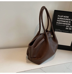 Détail du cabas en cuir marron foncé avec boucle métallique et texture grainée lychee