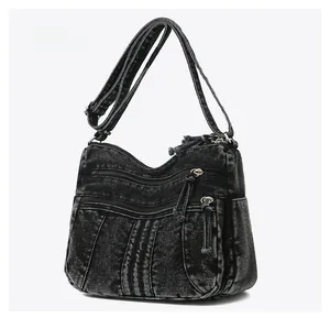 Détail du sac bandoulière en denim noir lavé avec plusieurs poches zippées et des textures