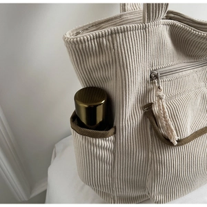 Close-up of corduroy tote bag showing side pocket and olive green ribbon detail