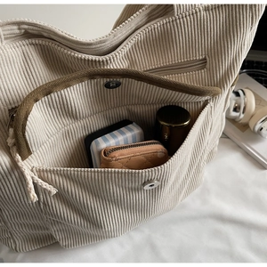 Detail view of corduroy tote bag front pocket with magnetic snap and internal storage