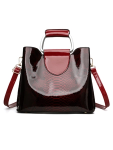 Detailed view of dark red patent leather handbag with crocodile pattern and silver U-handle