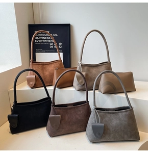 Multiple earth-toned minimalist underarm bags showing matte texture and teardrop pendant