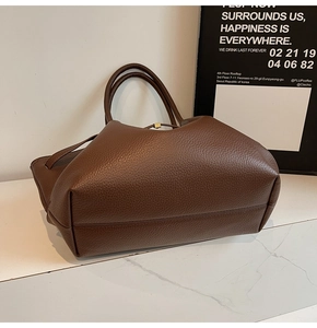 Détail du sac cabas en cuir grainé marron foncé avec boucle dorée sur marbre