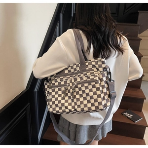 Detail of checkered tote bag with multiple zipper pockets and wide shoulder strap