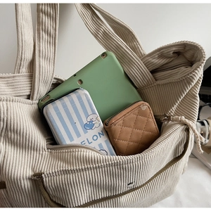 Detail view of corduroy tote bag showing large capacity with tablet and pockets