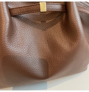 Gros plan détaillé sur le cuir grainé marron foncé et la boucle en métal doré