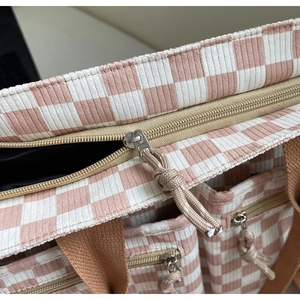 Detail of pink checkerboard corduroy tote bag showing metal zipper and fabric texture