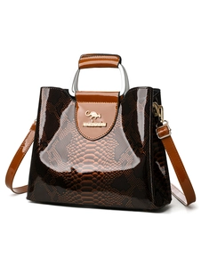 Detail of dark brown faux snake leather texture with silver metal ring handle on handbag