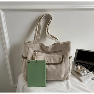 Detail of beige corduroy tote bag showing multiple pockets and spacious interior for laptop