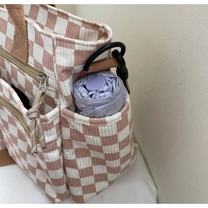 Detailed side pocket of pink checkered tote bag with a purple folding umbrella inside