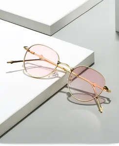 Macro shot of oval sunglasses with slim gold metal frames and translucent pink lenses