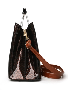 Detail of glossy snake pattern handbag with metal handle and textured finish