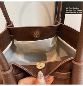 Détail du fermoir magnétique doré sur un sac cabas en cuir grainé marron