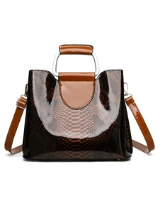Macro detail of glossy snake pattern texture and silver metal handle on brown handbag