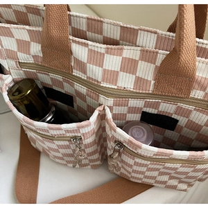 Detail of pink checkerboard corduroy tote bag showing front zipper pockets and storage