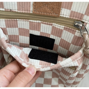 Detail of pink checkerboard corduroy tote bag showing zipper closure and velcro front pocket
