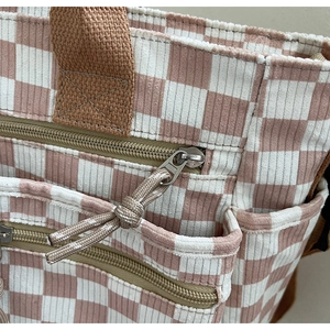 Close-up of pink checkered corduroy tote bag showing metal zipper and woven texture