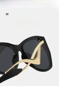 Detail of black sunglasses featuring unique golden wave-shaped hollow metal temples