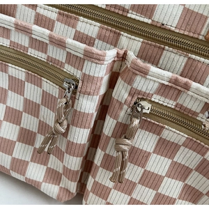Detail of pink checkerboard corduroy tote featuring front zip pockets and woven pullers