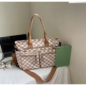 Brown checkerboard tote bag with multiple zip pockets, laptop and office props