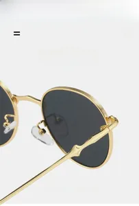 Detail of vintage oval sunglasses with textured gold metal frames and grey resin lenses