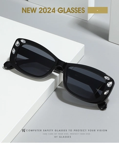 Close-up of black oval sunglasses with rhinestone accents on the temples and grey lenses