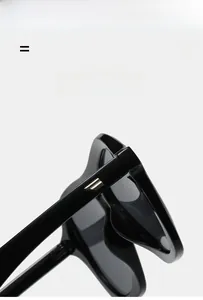 Detail of black aviator sunglasses showing gold geometric temple inserts and light frame