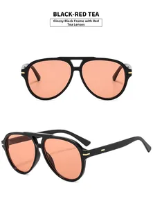 Detail of black aviator sunglasses with red-tea lenses and gold rivet metal accents