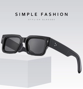 Detail of square black thick frame sunglasses with silver rivet accents on a pedestal