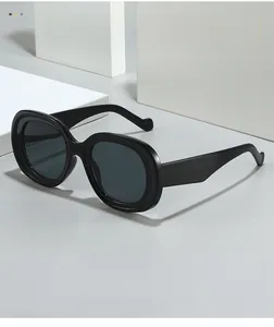Detail of vintage black oval sunglasses with wide temples on a minimalist geometric block