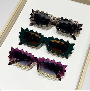 Detailed view of scalloped edge wavy sunglasses in leopard, green, and purple gradient