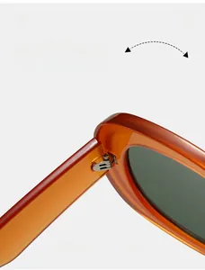 Macro detail of the durable metal hinge and thick amber frame of these oval sunglasses