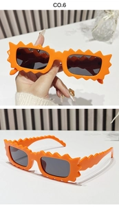 Macro detail of vibrant orange scalloped edge sunglasses with dark grey rectangular lenses