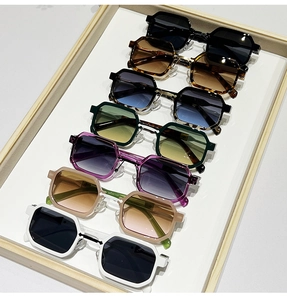 Detailed top view of hexagonal sunglasses in seven colors on a wooden tray