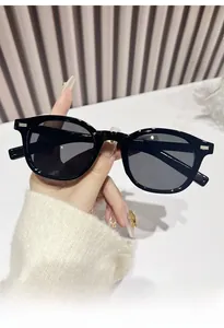 Detail of classic black oval sunglasses with metal rivet accents and protective grey lenses