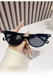 Detail of trendy retro cat-eye sunglasses with gold metal B logo on black frame